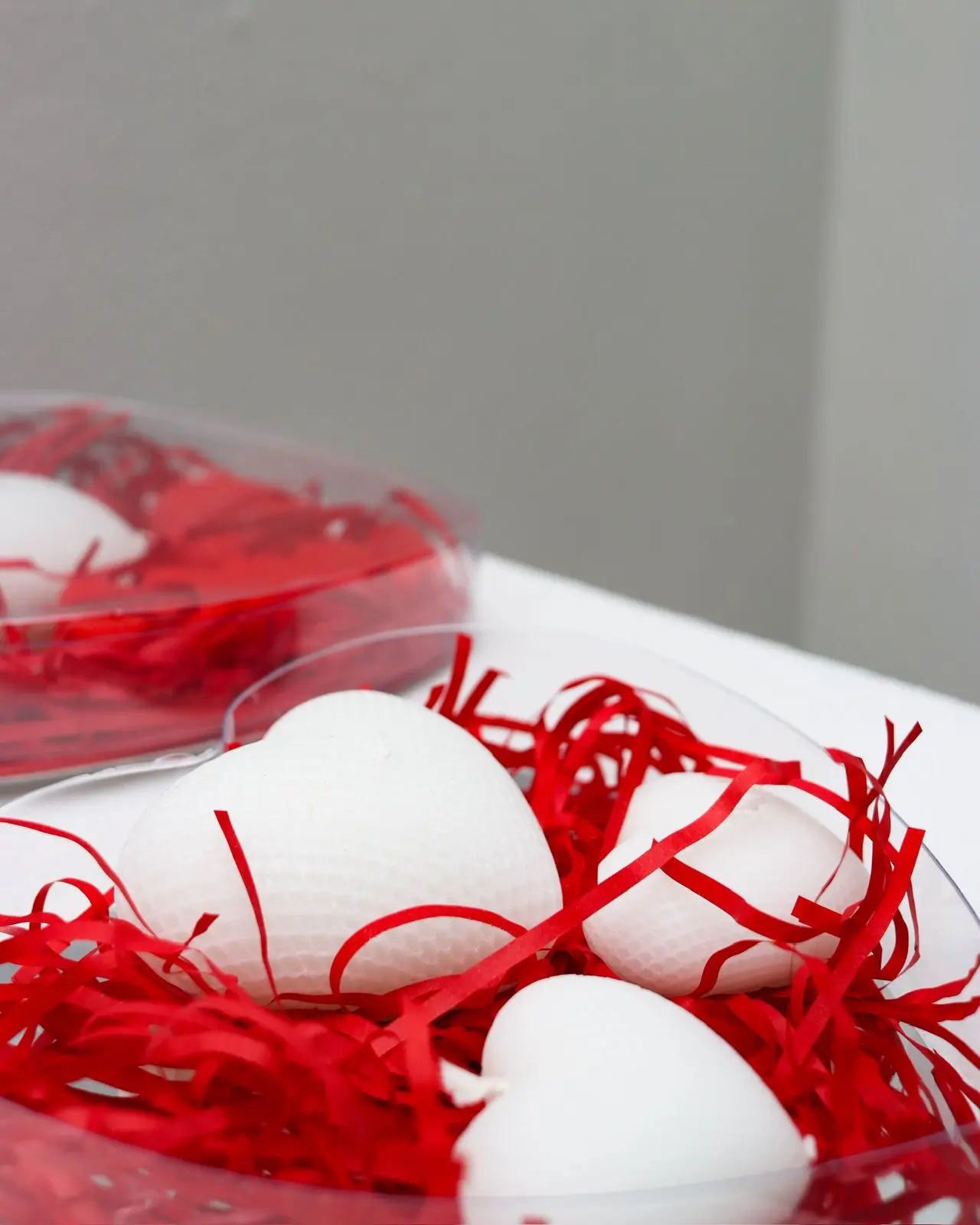Three white heart candles in a container.